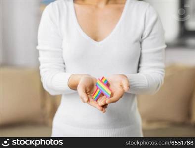homosexual and lgbt concept - close up of woman holding gay pride awareness ribbon. close up of woman holding gay awareness ribbon. close up of woman holding gay awareness ribbon