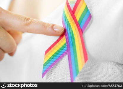 homosexual and lgbt concept - close up of woman showing gay pride awareness ribbon on her chest. woman with gay pride awareness ribbon on her chest. woman with gay pride awareness ribbon on her chest