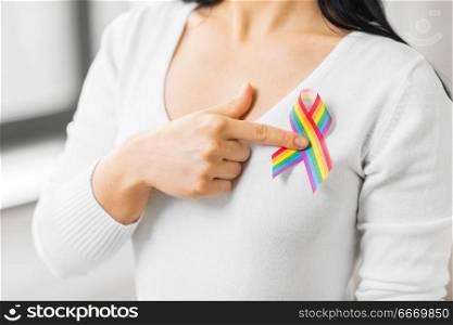 homosexual and lgbt concept - close up of woman showing gay pride awareness ribbon on her chest. woman with gay pride awareness ribbon on her chest. woman with gay pride awareness ribbon on her chest