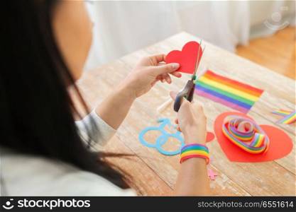 homosexual and lgbt concept - female hands with scissors cutting gay pride awareness ribbon. hands cutting gay awareness ribbon by scissors. hands cutting gay awareness ribbon by scissors