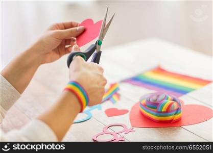 homosexual and lgbt concept - female hands with scissors cutting out red paper heart decoration for gay party. hands making heart decoration for gay party. hands making heart decoration for gay party