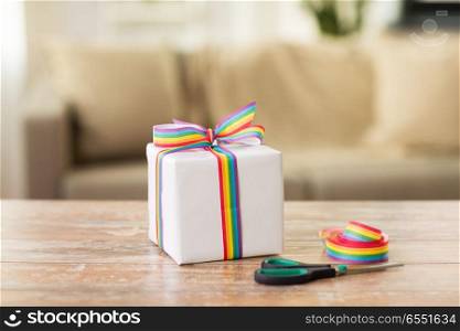 homosexual and lgbt concept - gift box, gay pride awareness ribbon and scissors on wooden table. present, gay awareness ribbon and scissors. present, gay awareness ribbon and scissors