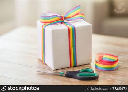 homosexual and lgbt concept - gift box, gay pride awareness ribbon and scissors on wooden table. present, gay awareness ribbon and scissors. present, gay awareness ribbon and scissors