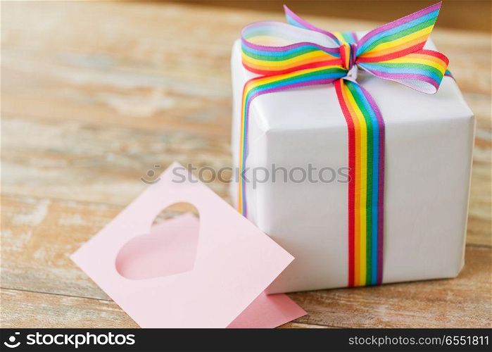 homosexual and lgbt concept - gift box with gay pride awareness ribbon and greeting card on wooden table. gift with gay awareness ribbon and greeting card. gift with gay awareness ribbon and greeting card