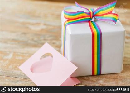 homosexual and lgbt concept - gift box with gay pride awareness ribbon and greeting card on wooden table. gift with gay awareness ribbon and greeting card. gift with gay awareness ribbon and greeting card