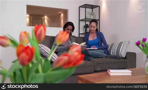 Homosexual couple, gay people, lesbian women, same sex marriage relationship between Asian girls. Multi ethnic friends using ipad on sofa at home, happy girlfriend showing tablet to female partner