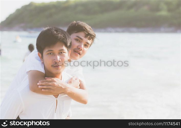 Homosexual portrait young asian couple riding the neck together with enjoy and fun on beach in summer, asia gay cheerful going sea for leisure with romantic and happy vacation at sea, LGBT with legal.