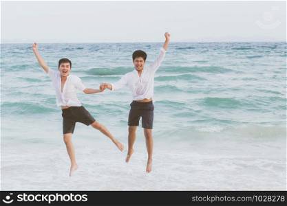 Homosexual portrait young asian couple running and jump with cheerful together on beach in summer, asia gay going tourism for leisure and relax with happiness in vacation at sea, LGBT legal concept.