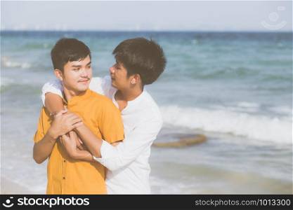 Homosexual portrait young asian couple standing hug together on beach in summer, asia gay going tourism for leisure and relax with romantic and happiness in vacation at sea, LGBT concept.