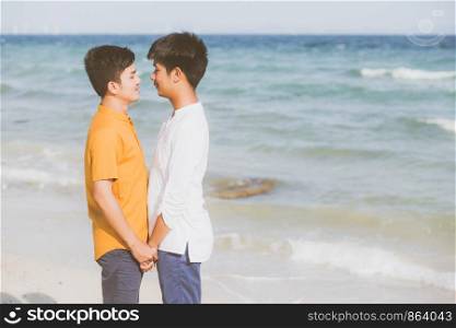 Homosexual portrait young asian couple standing together on beach in summer, asia gay holding hands going sea for leisure and relax with romantic and happy in vacation at sea, LGBT with legal concept.
