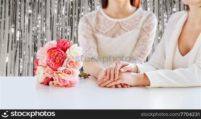 homosexuality, same-sex marriage and lgbt concept - close up of happy married lesbian couple with flower bunch on wedding over foil party curtain on background. close up of happy lesbian couple with flowers