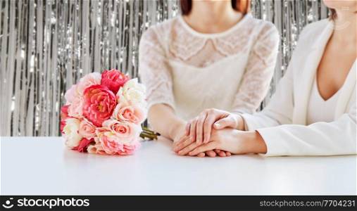 homosexuality, same-sex marriage and lgbt concept - close up of happy married lesbian couple with flower bunch on wedding over foil party curtain on background. close up of happy lesbian couple with flowers