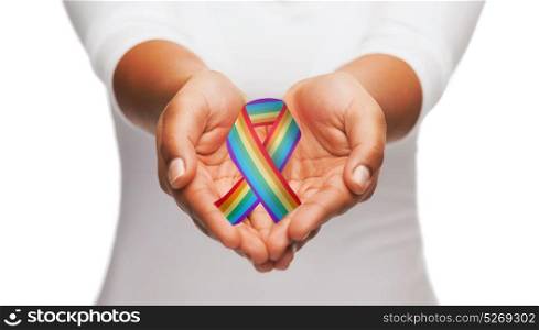 homosexuality, support and charity concept - african american woman hands holding rainbow gay pride awareness ribbon. hands holding rainbow gay pride awareness ribbon