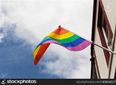 homosexuality, symbolic and gay pride concept - close up of rainbow flag waving on building