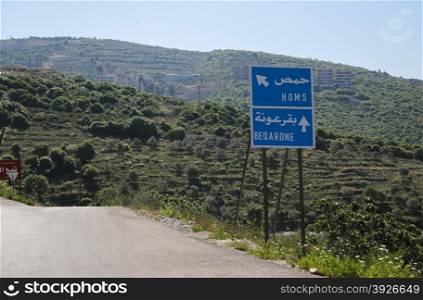 Homs; road sign; war; syria; city; middle; people; east; scene; urban; ethnicity; eastern; outdoors; politics; islam; land; horizontal; conflict; poverty; man; border; international; arabia; emigration; waiting; transportation; immigration; europe; travel; made; structure; women; immigrant; child; building; syrian; retro; construction; arabic; baby; backgrounds; map; Homs road sign in Syria