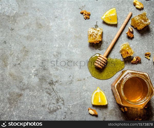Honey background. Natural honey with slices of lemon and walnuts. On the stone table.. Honey background. Natural honey with slices of lemon and walnuts.