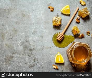 Honey background. Natural honey with slices of lemon and walnuts. On the stone table.. Honey background. Natural honey with slices of lemon and walnuts.