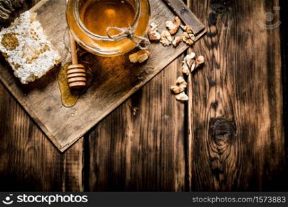 Honey background. Sweet honey in the comb, glass jar with nuts. On wooden background.. Sweet honey in the comb, glass jar with nuts.