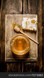Honey background. The jar of honey, honey comb and spoon on a wooden Board. On wooden background.. The jar of honey