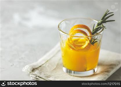 Honey bourbon cocktail with rosemary simple syrup or homemade whiskey sour cocktail drink with orange and rosemary. Decorate orange peel. Light concrete surface.