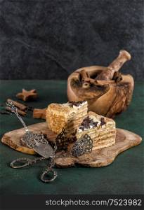 Honey cake with spices and vintage tools on dark background. Sweet food