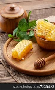 honey comb in a wooden bowl on a background of wooden boards with a place for text