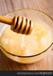 Honey dripping in glass bowl on wooden table