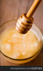 Honey dripping in glass bowl on wooden table