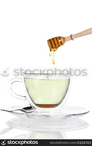 honey drops from a honey dipper in glass cup with green tea. honey drops from a honey dipper in glass cup with green tea on white background