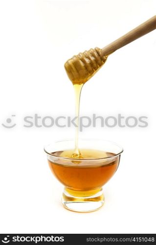 Honey in a glass bowl with a wooden stick