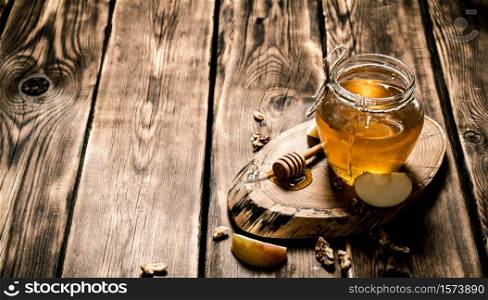 Honey in a jar with nuts and Apple slices. On wooden background.. Honey in a jar with nuts and Apple slices.