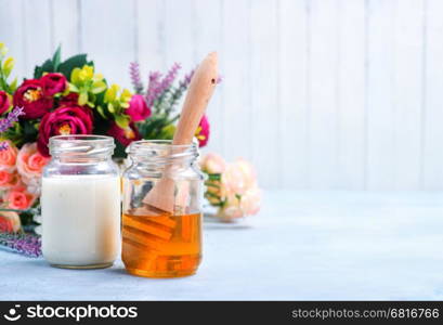 honey in glass bank and milk on a table