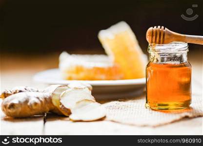 Honey in jar with honey dipper ginger and on wooden and honeycomb on white plate background