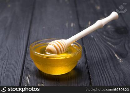 Honey in jar with honey dipper on wooden background