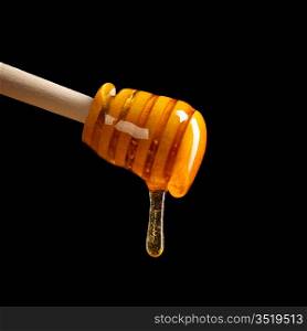 honey is dripping from the spoon against black background