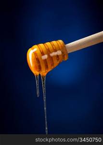 honey is dripping from the spoon against blue background