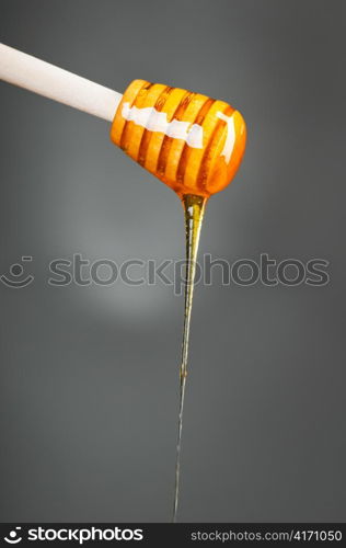 honey is dripping from the spoon, on gray background