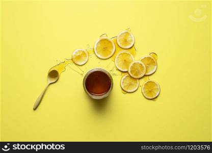 Honey jar and lemon slices with honey on them, on yellow background. Flat lay of lemons and honey. Natural cold remedy. Detox and immunity treatment.