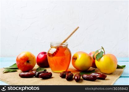 Honey jar, dates and ripe apples on burlap napkin. Honey jar, dates and fresh apples with green leaves on the burlap napkin. Rosh hashanah concept. Jewesh new year symbols.