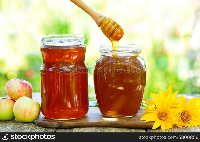 Honey pouring into glass jar on wooden table