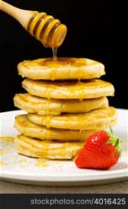 Honey pouring over pancakes