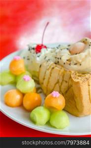 Honey toast topped with ice cream cantaloupe and melon on dish. Melon toast