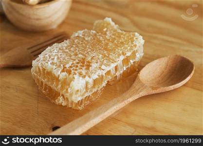 honey with honeycomb and dipper on wooden table