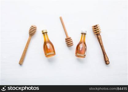 Honey wooden dipper and little honey bottle on white wooden background.