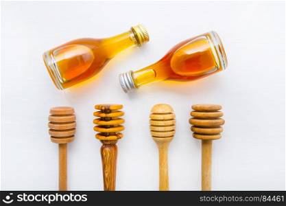 Honey wooden dipper and little honey bottle on white wooden background.