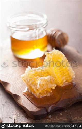 honeycomb dipper and glass jar on wooden background