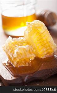 honeycomb dipper and honey in jar on wooden background