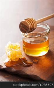 honeycomb dipper and honey in jar on wooden background