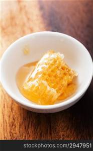 honeycomb in bowl over wooden background