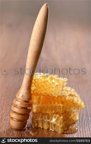 honeycombs and drizzler on wooden background